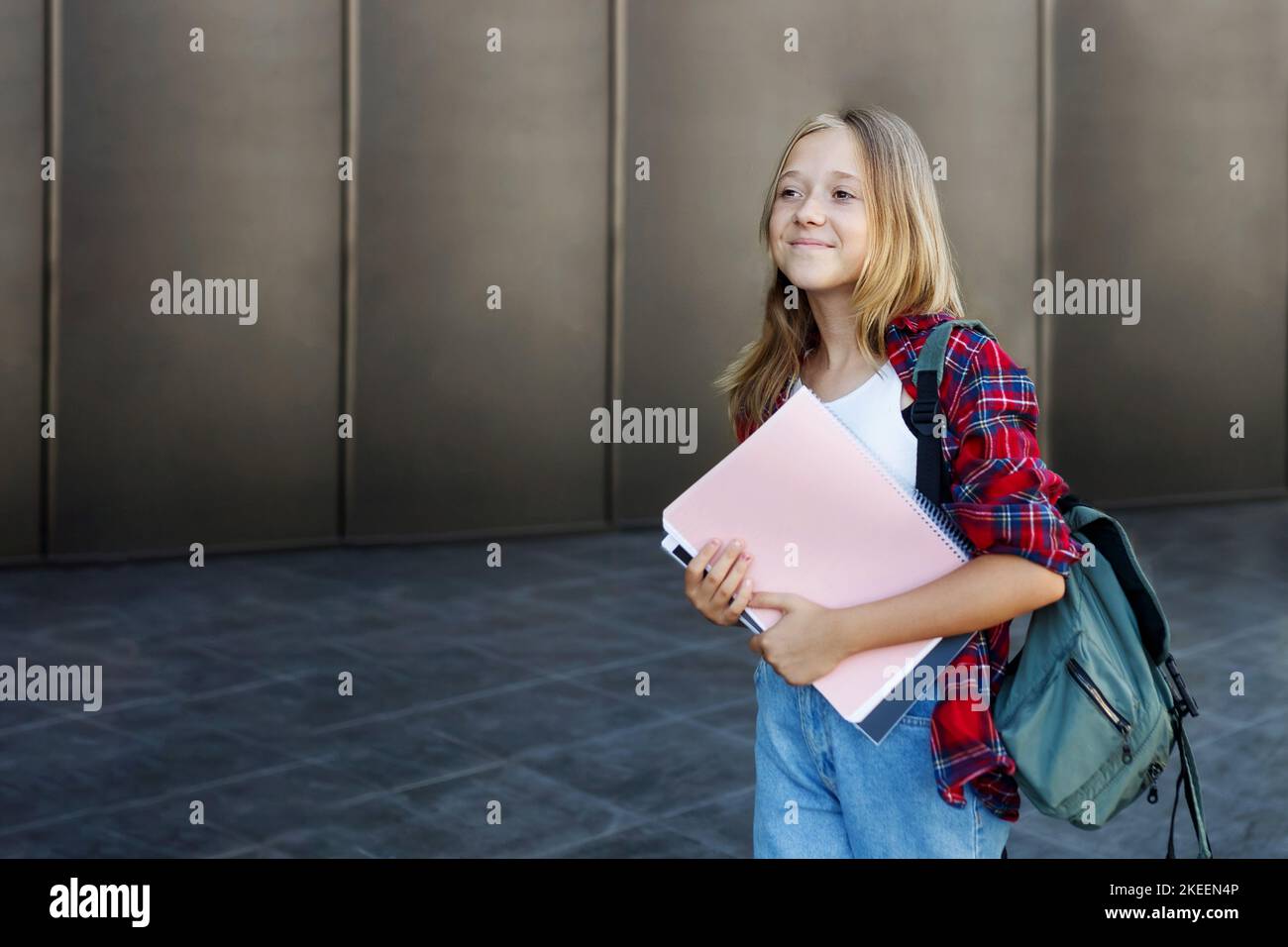 Niedliche 13 Jahre Mädchen Student Teenager mit einem Rucksack hält Notizblöcke und Notizbücher auf der Straße Stockfoto