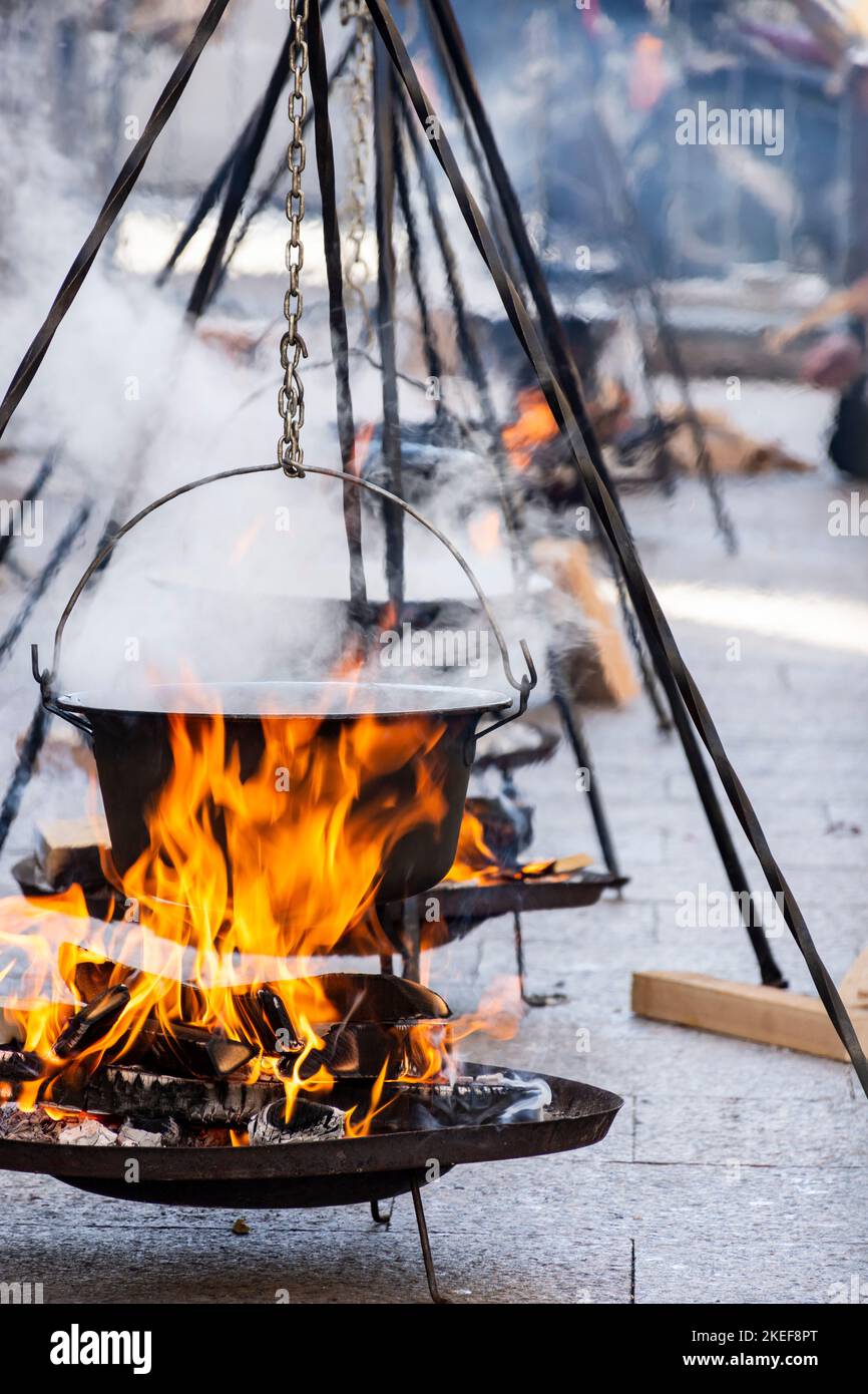 Eine vertikale Aufnahme dampfender, brennender Kochstative, auf denen Gulasch an kalten Tagen zubereitet wird Stockfoto