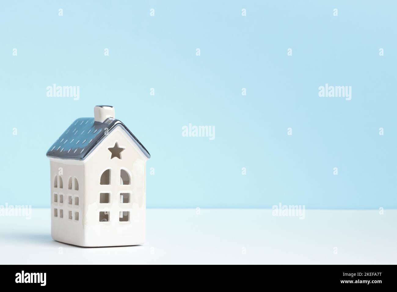 Kleines Keramikhaus auf dem Tisch auf blauem Hintergrund. Dekoration im Wohnstil. Stockfoto