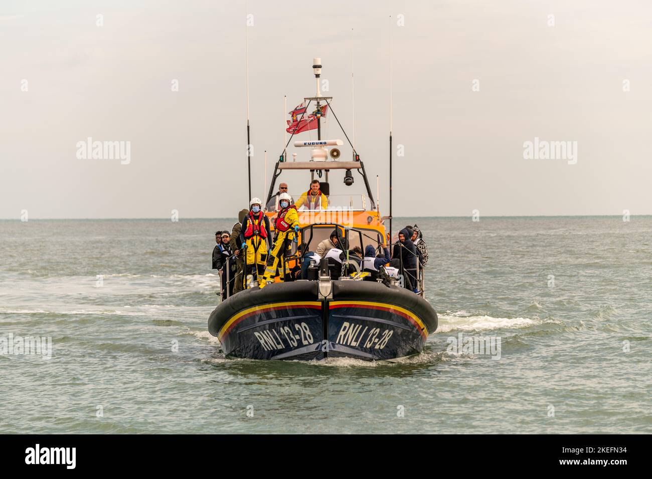 Migranten, die von der RNLI im Ärmelkanal auf See abgeholt wurden und am Strand von Dungeness ankommen, Stockfoto