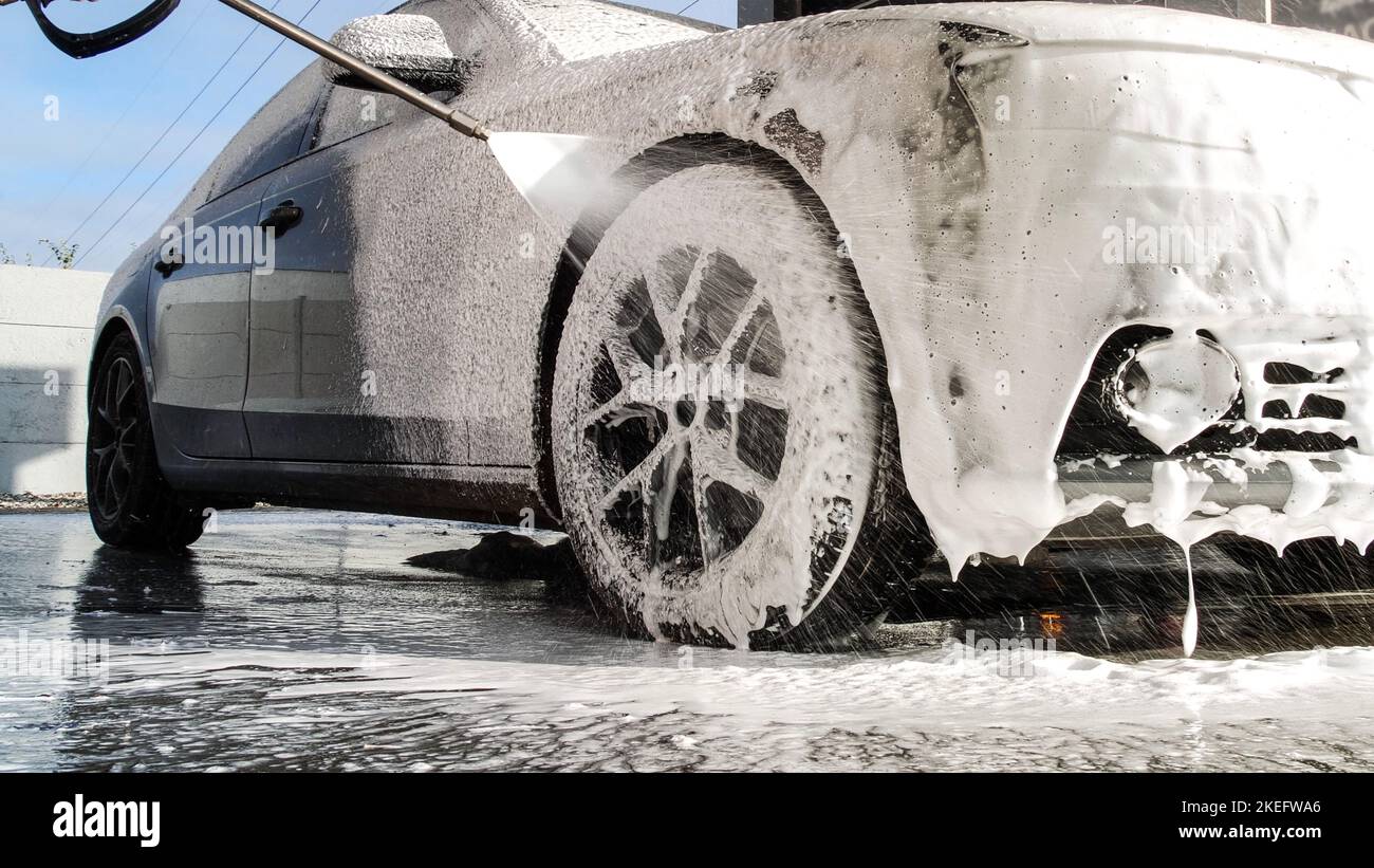 Waschen Sie ein Luxusauto mit einer berührungslosen Autowäsche. Waschen von Limousinen mit Schaum und Hochdruckwasser. Frühjahrsputz in einer Autowäsche. Stockfoto