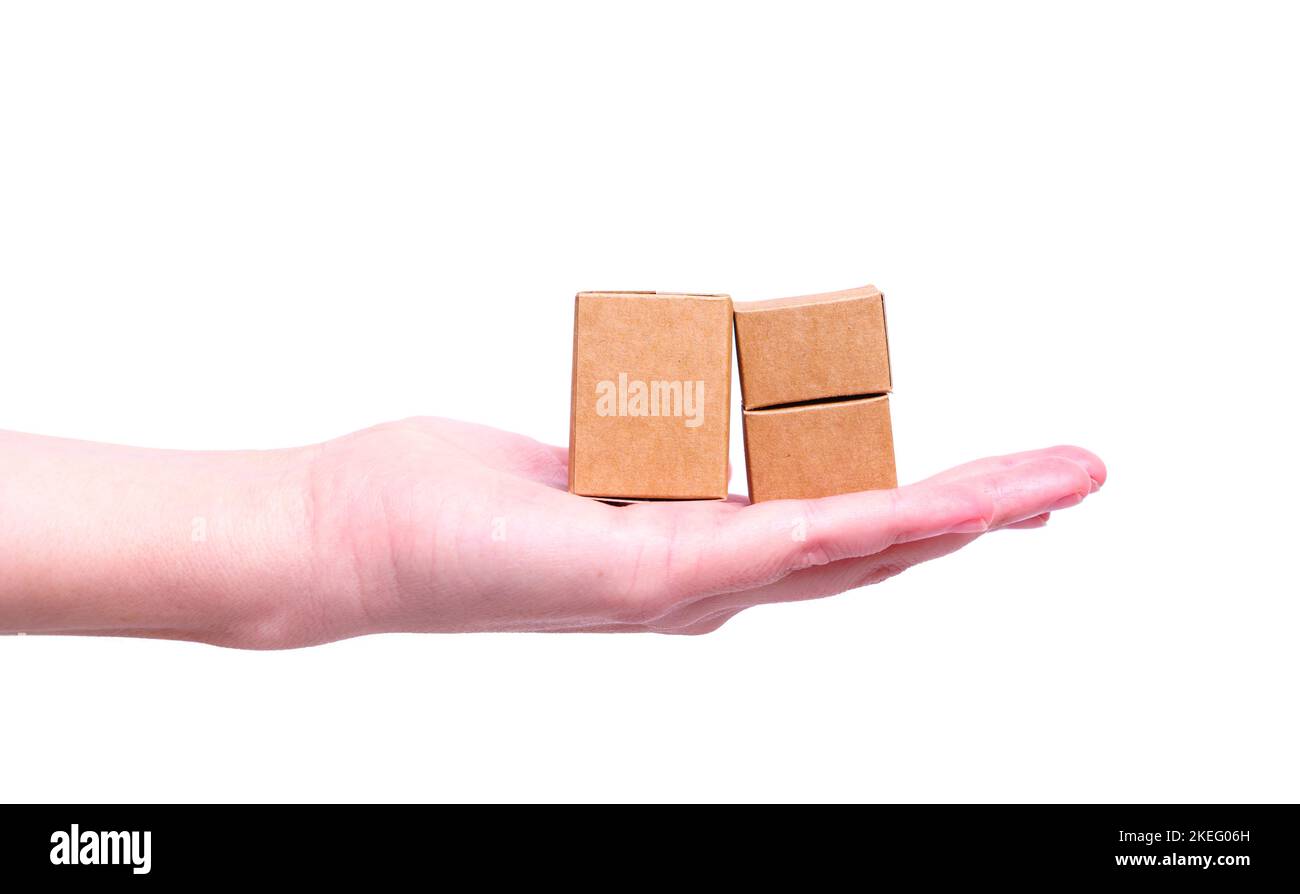 Kleine braune Versandkartons aus Papier, die isoliert auf weißem Hintergrund auf der Hand eines Weibchens platziert sind. Kreatives Lieferkonzept. Stockfoto