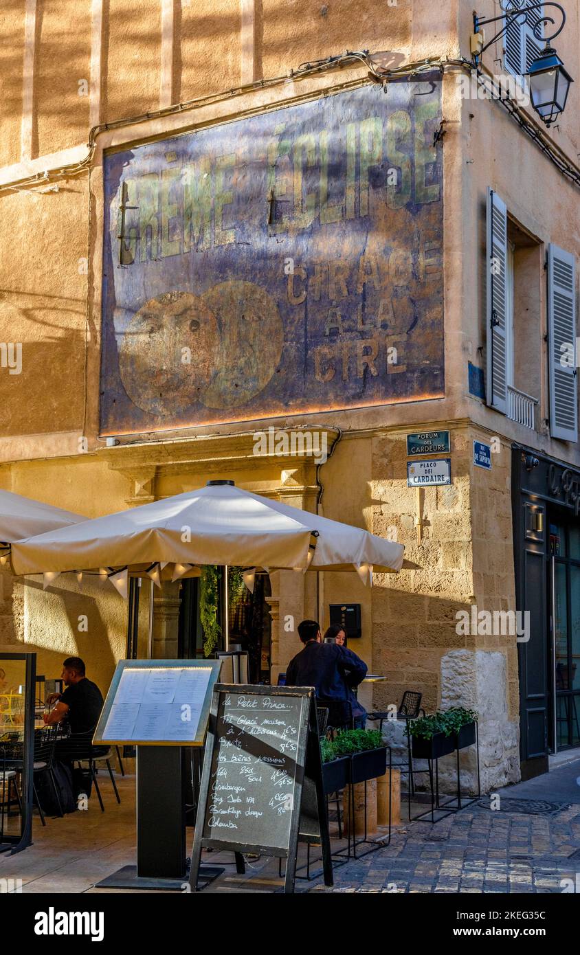 Menschen, die in einem Restaurant im Freien mit einem verblassten Werbeschild an der Wand essen, Aix-en-Provence, Provence-Alpes-Cote d'Azur, Frankreich, Westeuropa Stockfoto