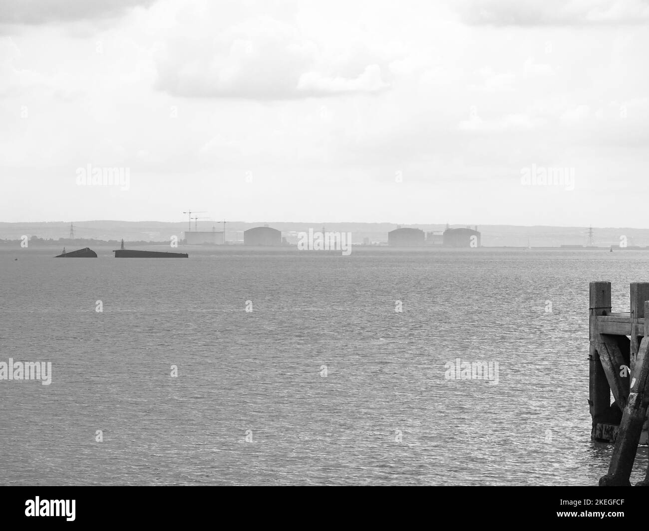 Geschichtete Ansicht der industriellen Küste mit Überresten im Wasser Stockfoto