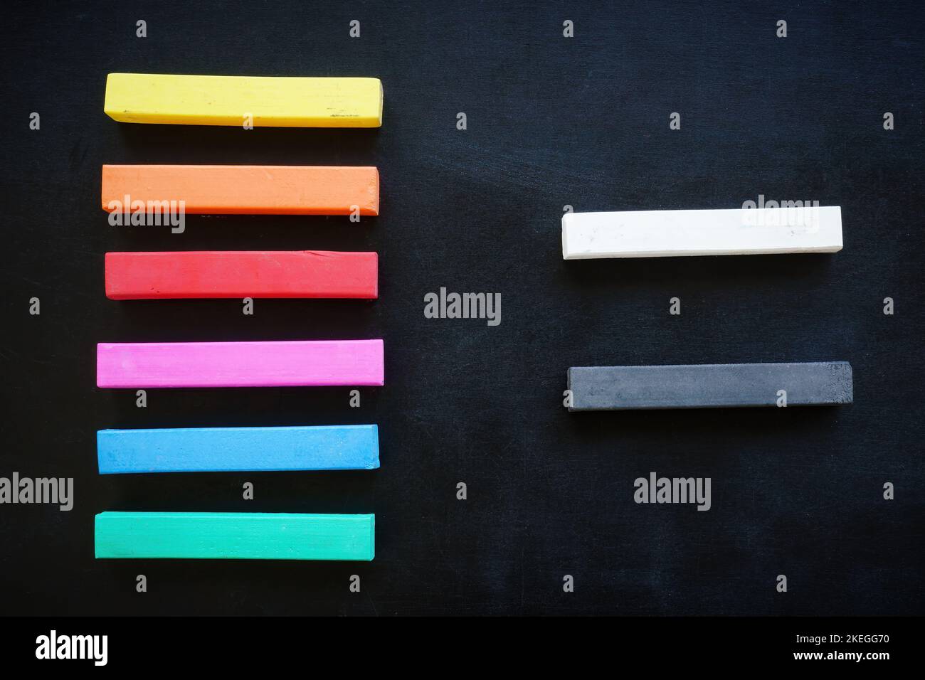 Mehrfarbige Buntstifte liegen neben Schwarz und Weiß als Symbol der Vielfalt. Stockfoto