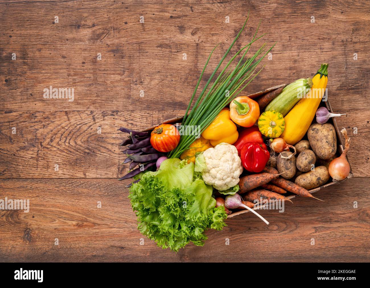 Box mit frischem Gemüse aus dem Garten auf rustikalem Holztisch. Draufsicht. Hochauflösendes Produkt. Stockfoto
