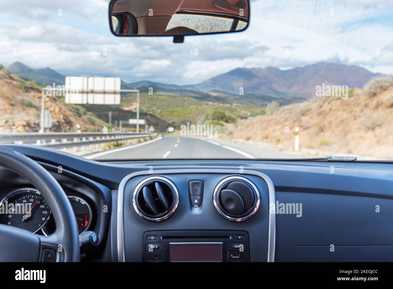 Blick auf die Autobahn und eine Berglandschaft aus dem Inneren eines fahrenden Autos. Stockfoto