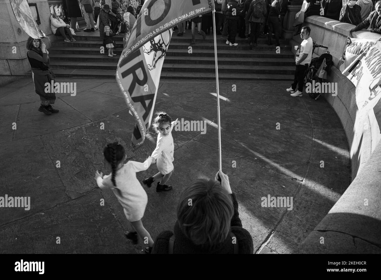 12. November 2022. Zwei junge Mädchen tanzen bei einer Kundgebung in London unter einer iranischen Protestflagge. Stockfoto