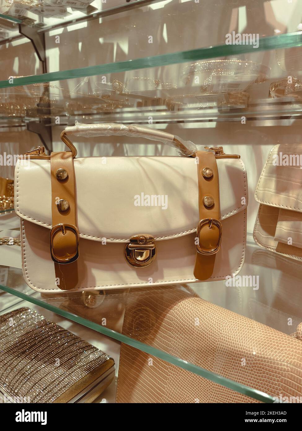 Modische weiße und braune Farbe Frau kleine Handtasche auf dem Geschäft Glasregal. Stockfoto