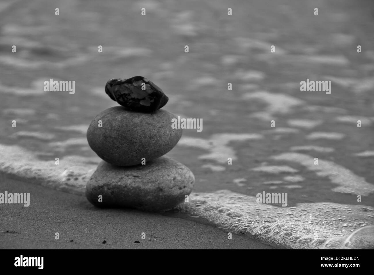 Eine Graustufenaufnahme von Zen-Steinen am Strand Stockfoto