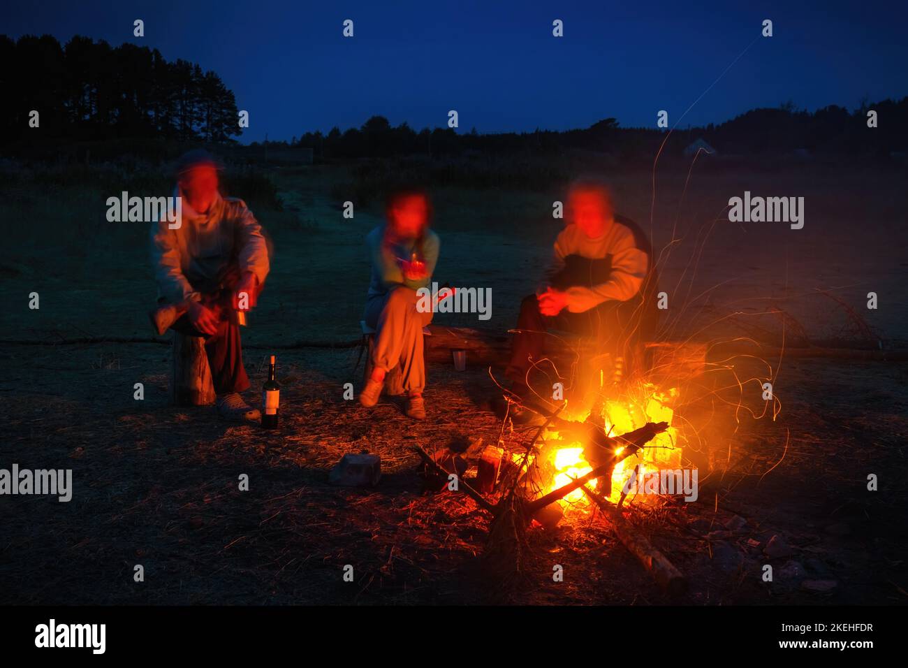 Freunde in der Nähe von Lagerfeuer auf dem Campingplatz. Stockfoto