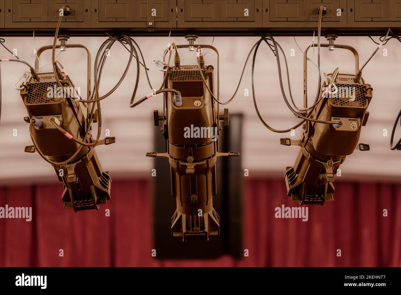 Nahaufnahme von drei neuen großen Theaterspots, die in einem älteren Theater oder Auditorium aufgehängt wurden. Stockfoto