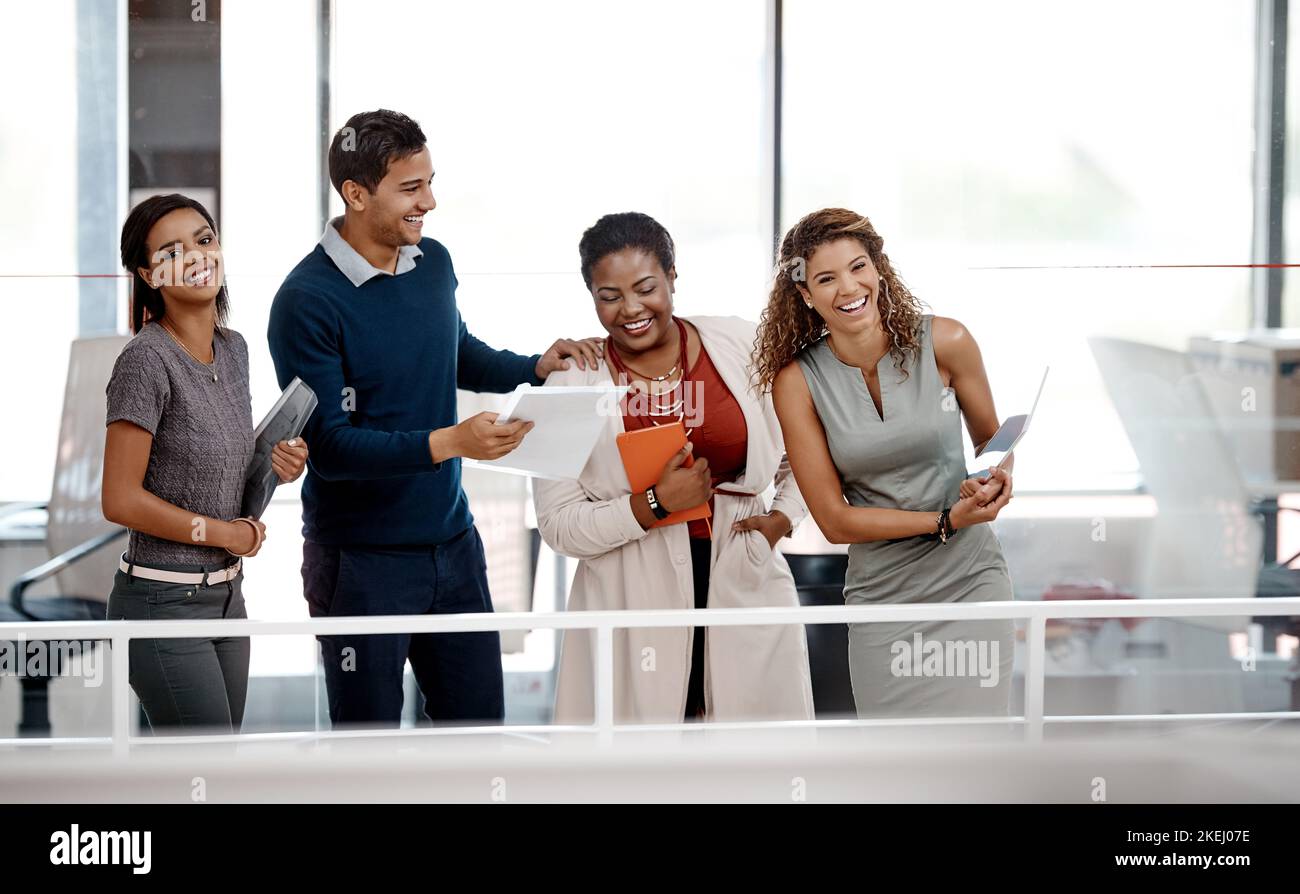 Eine glückliche junge Gruppe von Kollegen, die gemeinsam im Büro lachen. Stockfoto