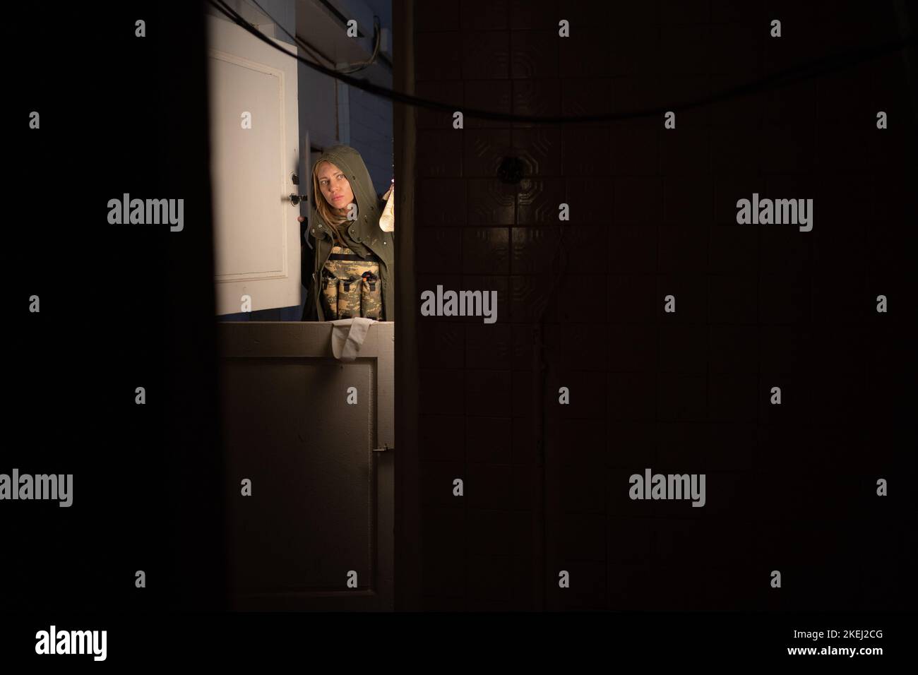 Eine schmutzige, müde Stalkerin mit Laterne geht in einem verlassenen Raum auf der Suche nach Nahrung umher. Post-Apokalypse. Wandern in einer post-apokalyptischen Welt. Stockfoto