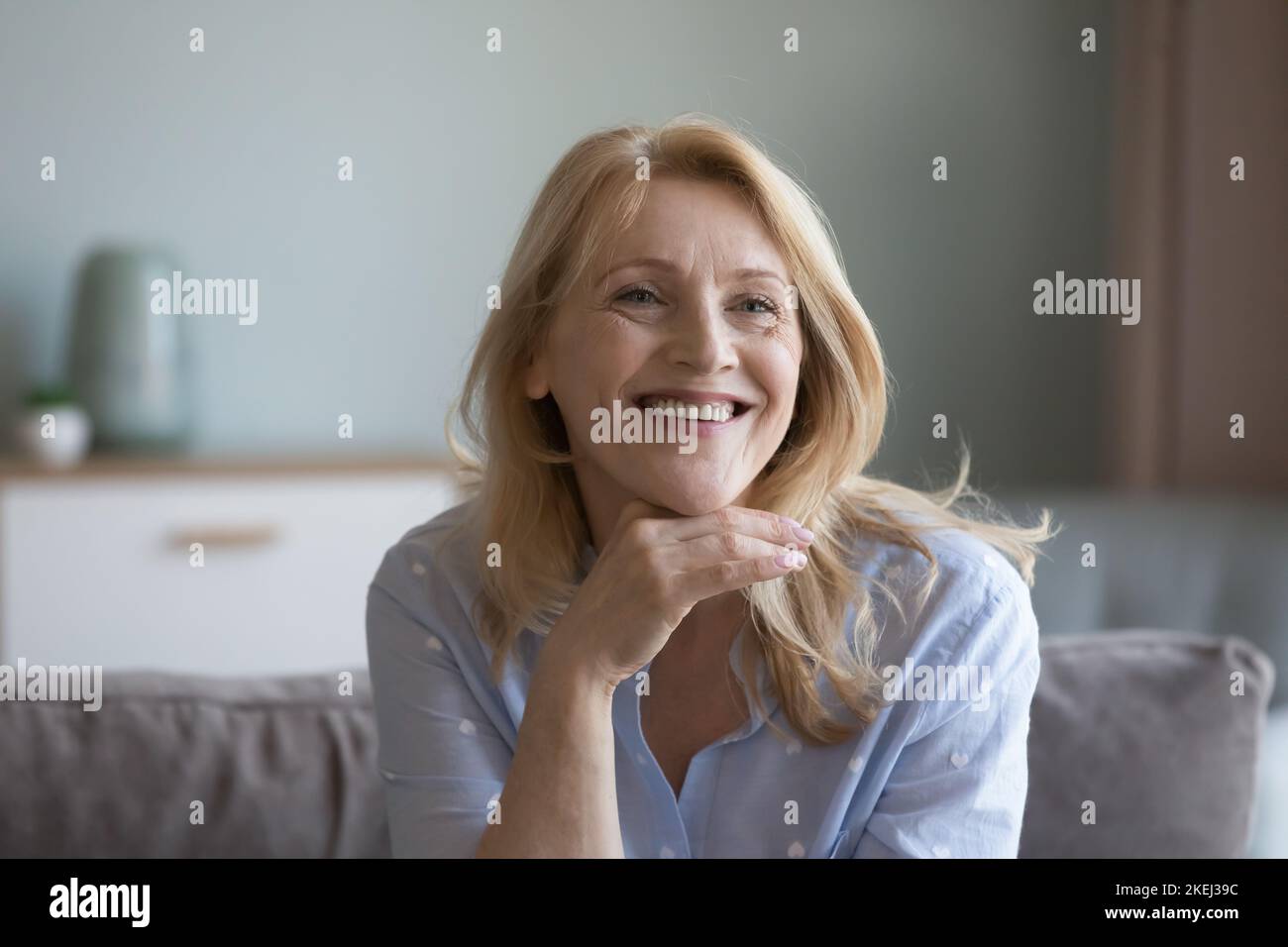 Portrait glückliche ältere blonde Frau, die sich zu Hause auf der Couch ausruht Stockfoto