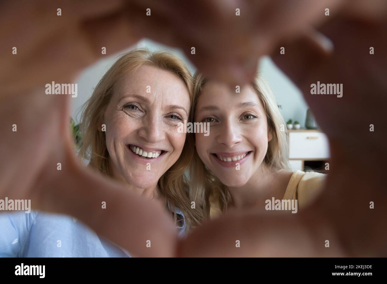 Glückliche reife Frau und junge Erwachsene Tochter zeigt Herz-Symbol Stockfoto