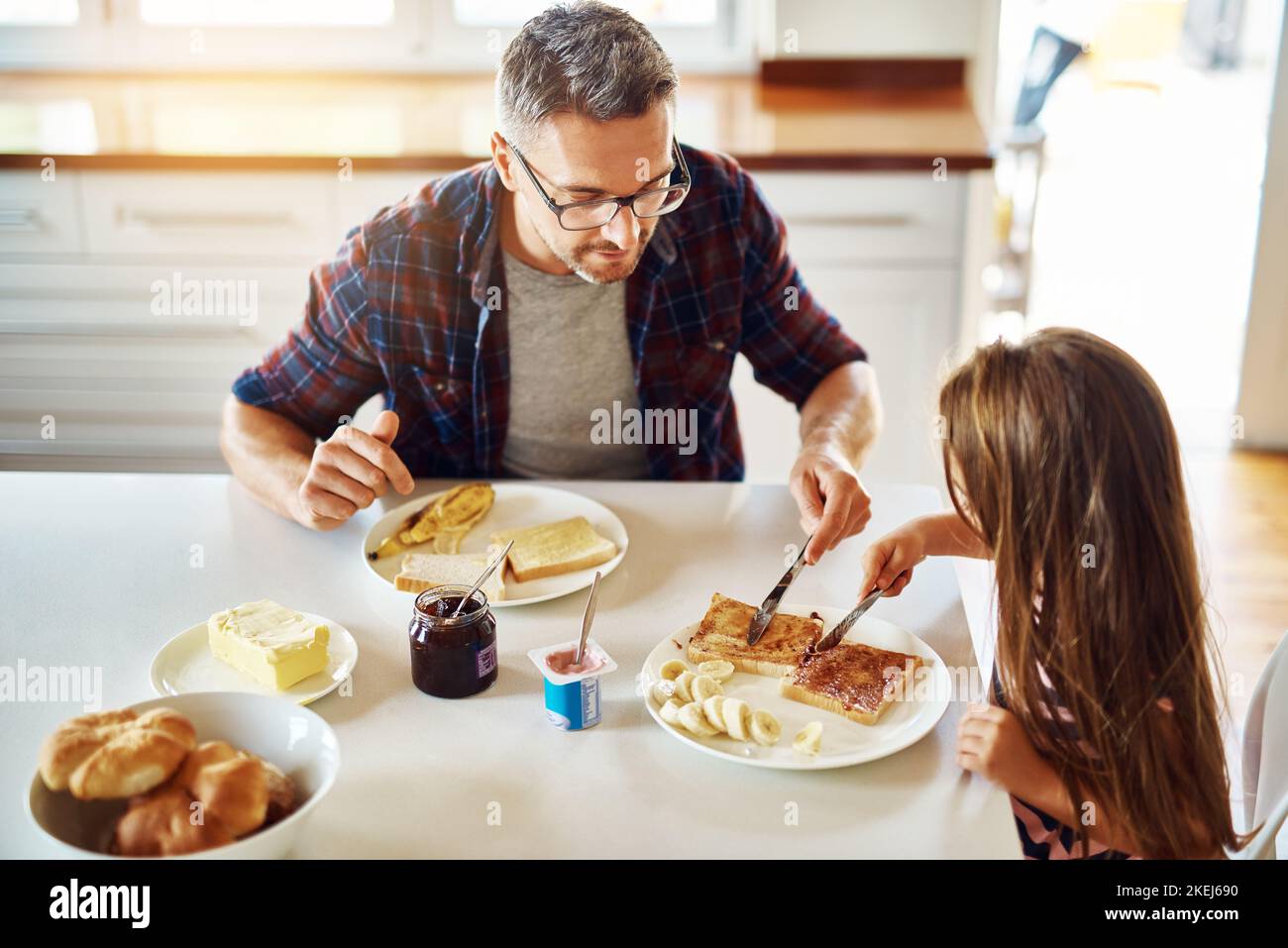 Lasst mich ein paar haben... ein entzückendes kleines Mädchen, das mit ihrem Vater in der Küche frühstückt. Stockfoto