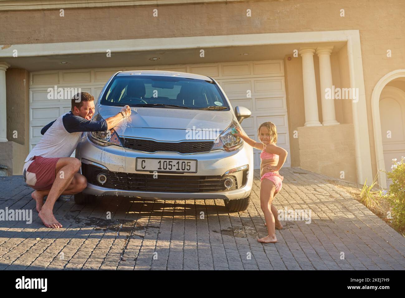 Ein Vater und eine Tochter haben Spaß beim Waschen eines Autos. Stockfoto