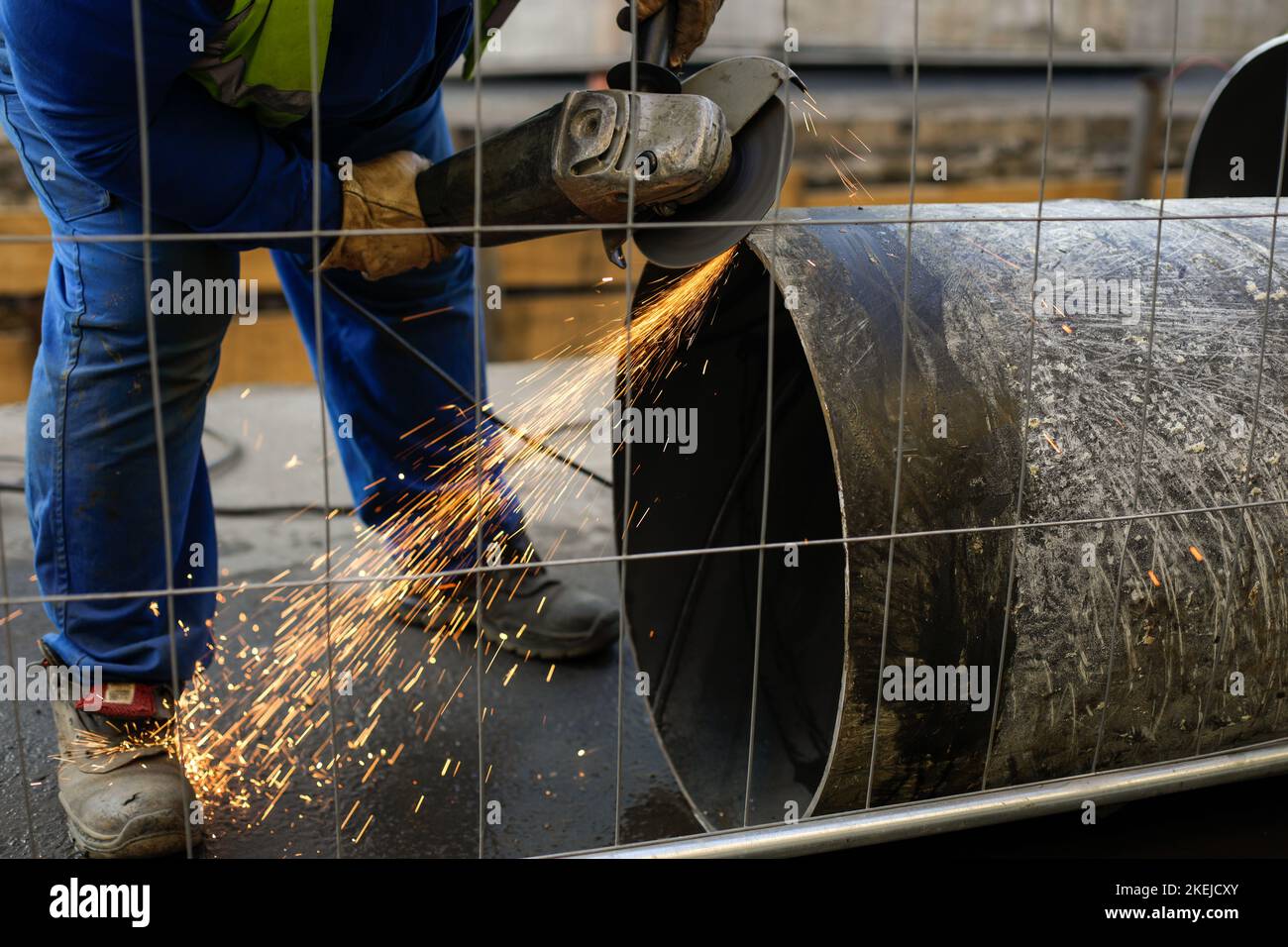 Details zur geringen Schärfentiefe (selektiver Fokus) mit einem Arbeiter, der einen Winkelschleifer auf einer industriellen Metallrohrleitung verwendet. Stockfoto