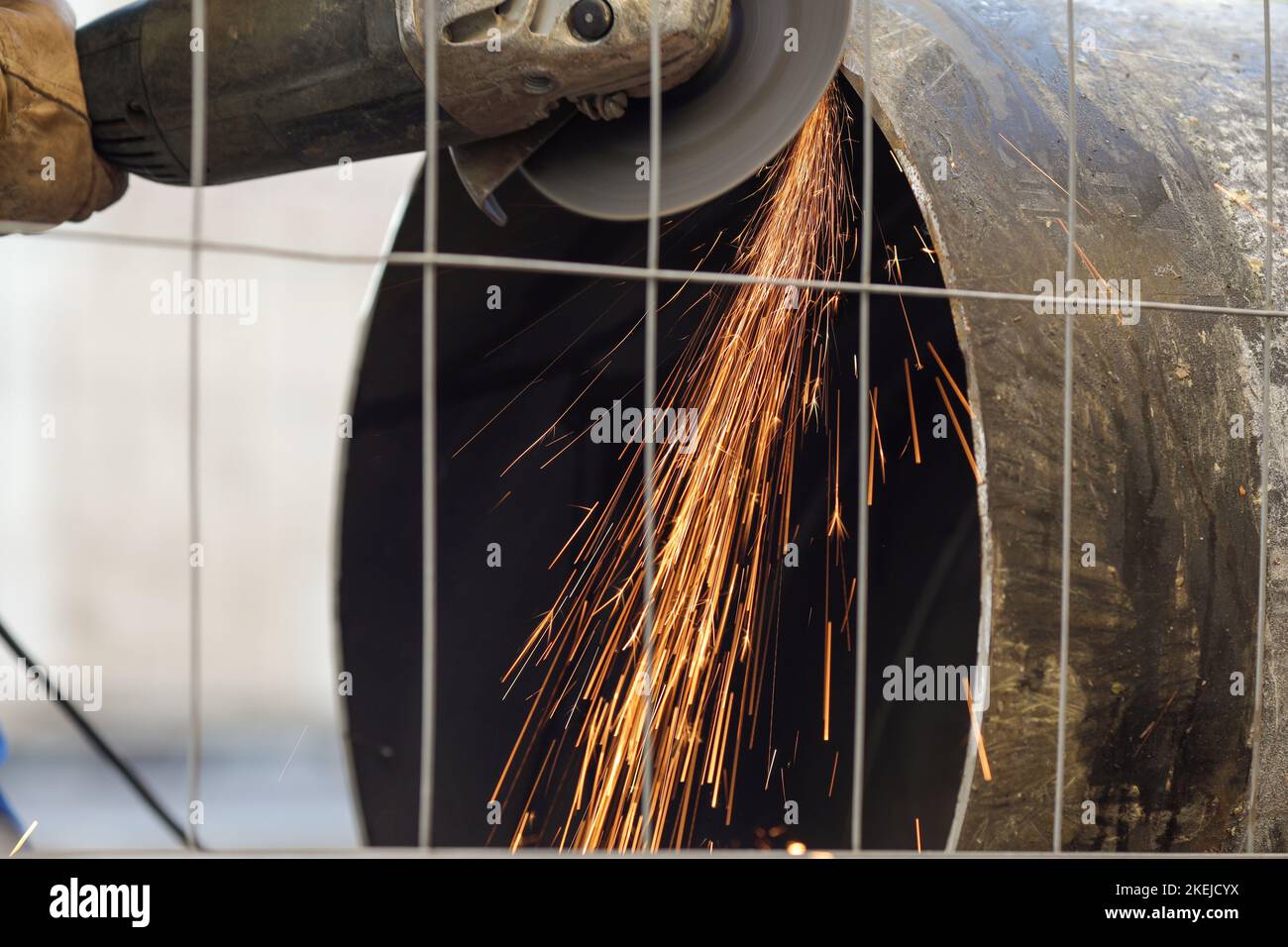 Details zur geringen Schärfentiefe (selektiver Fokus) mit einem Arbeiter, der einen Winkelschleifer auf einer industriellen Metallrohrleitung verwendet. Stockfoto