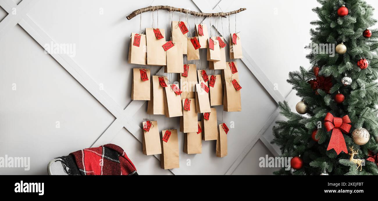 Weihnachtsbaum und kreativer Adventskalender hängen an der hellen Wand zu Hause Stockfoto