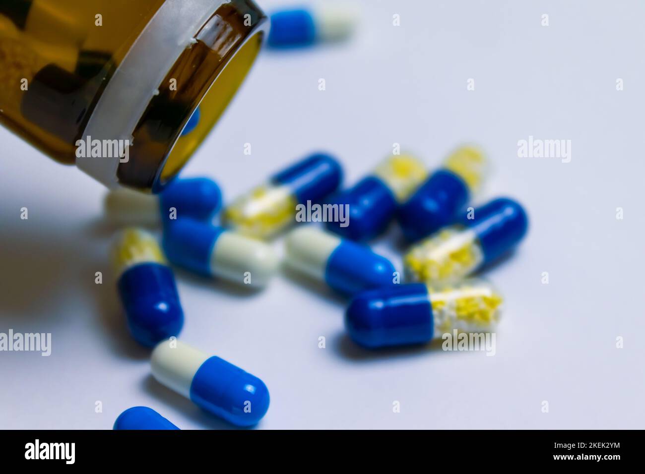 Ein Medizinglas mit verschütteten Pillen, die auf einer weißen Oberfläche liegen - Konzept von Apotheken und Gesundheit Stockfoto