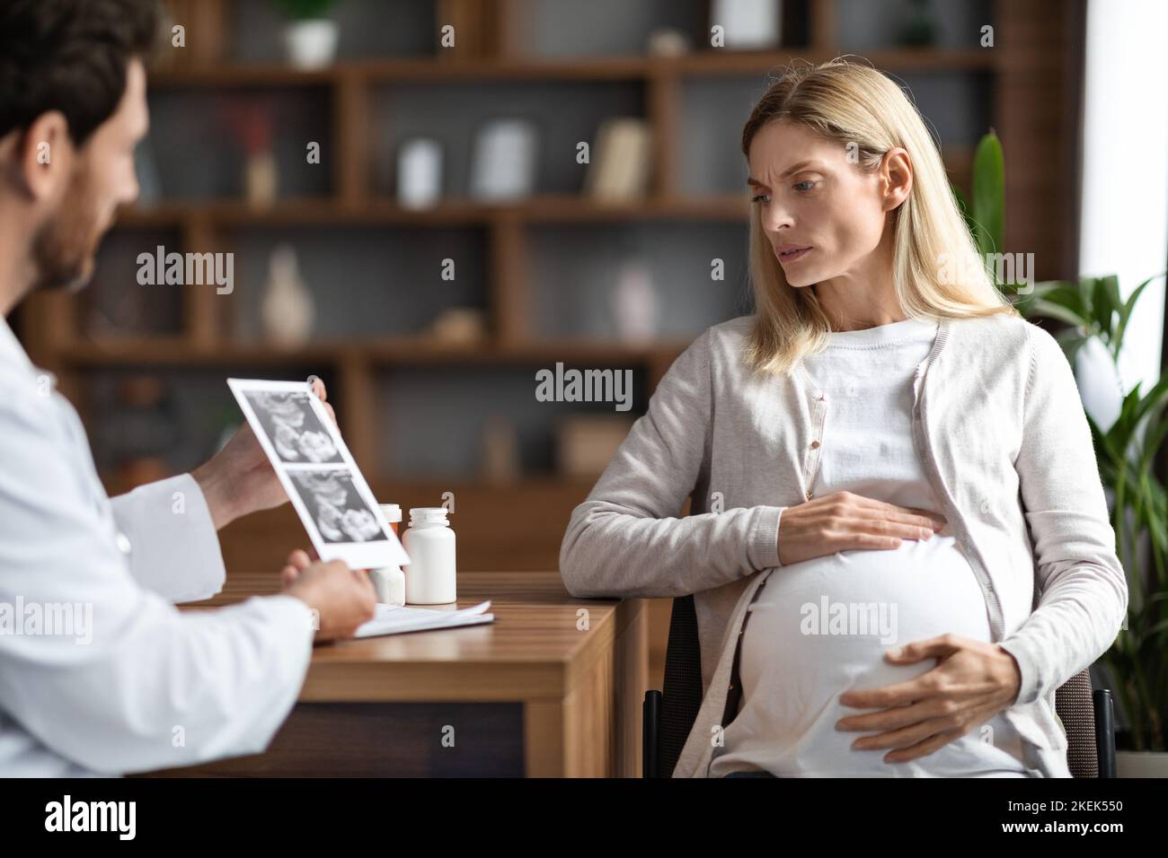 Männlicher Gynäkologe Arzt Zeigt Baby-Sonographie-Bild Zu Besorgt Schwanger Frau Stockfoto