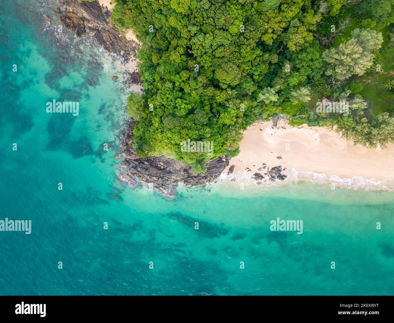 Luftaufnahme von oben auf den tropischen Strand mit türkisfarbenem Wasser, weißem Sand und großen Felsen. Bäume und Palmen wachsen auf dem Felsen. Tropisches Thema. Stockfoto
