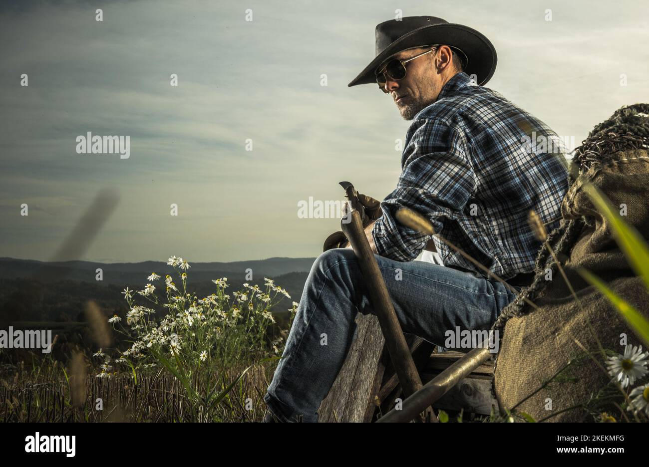 American Cowboy im Alter von 40s Jahren genießt Freizeit auf seiner Countryside Ranch. Sitzen auf einem Stück Holzkratte. Stockfoto