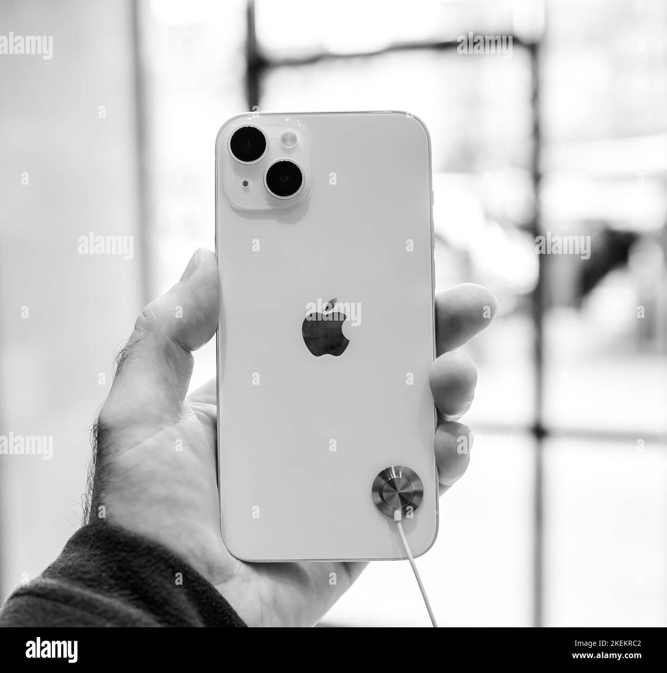 Paris, Frankreich - 28. Okt 2022: Männliche Hand mit neuem leistungsstarken, goldfarbenen iPhone 14 plus neuem Smartphone von Apple Computers Rückansicht mit Doppelkamera - Schwarz-Weiß-Bild Stockfoto