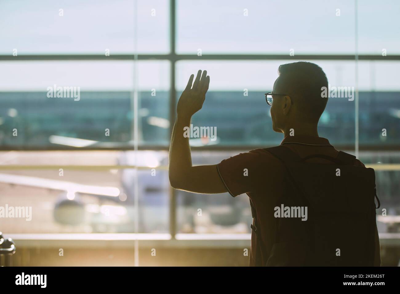 Sagen Sie Auf Wiedersehen am Flughafen. Der zurücklassende Mann winkt mit der Hand. Stockfoto