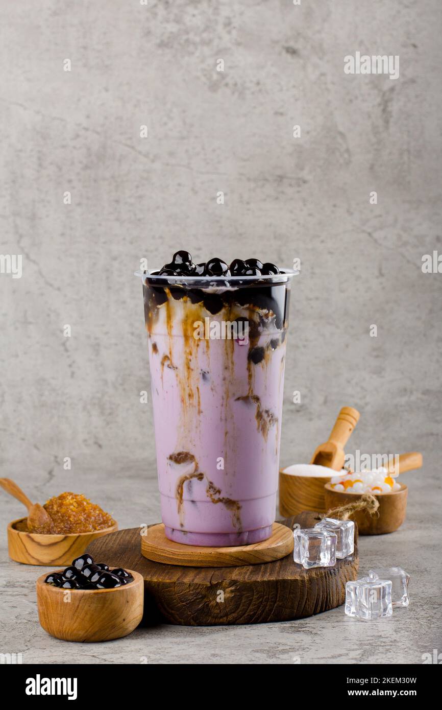 Boba oder Tapioka Perlen ist taiwan Bubble Milch Tee in Kunststoff-Tasse mit Taro-Geschmack auf Textur Hintergrund, Sommer Erfrischung. Stockfoto