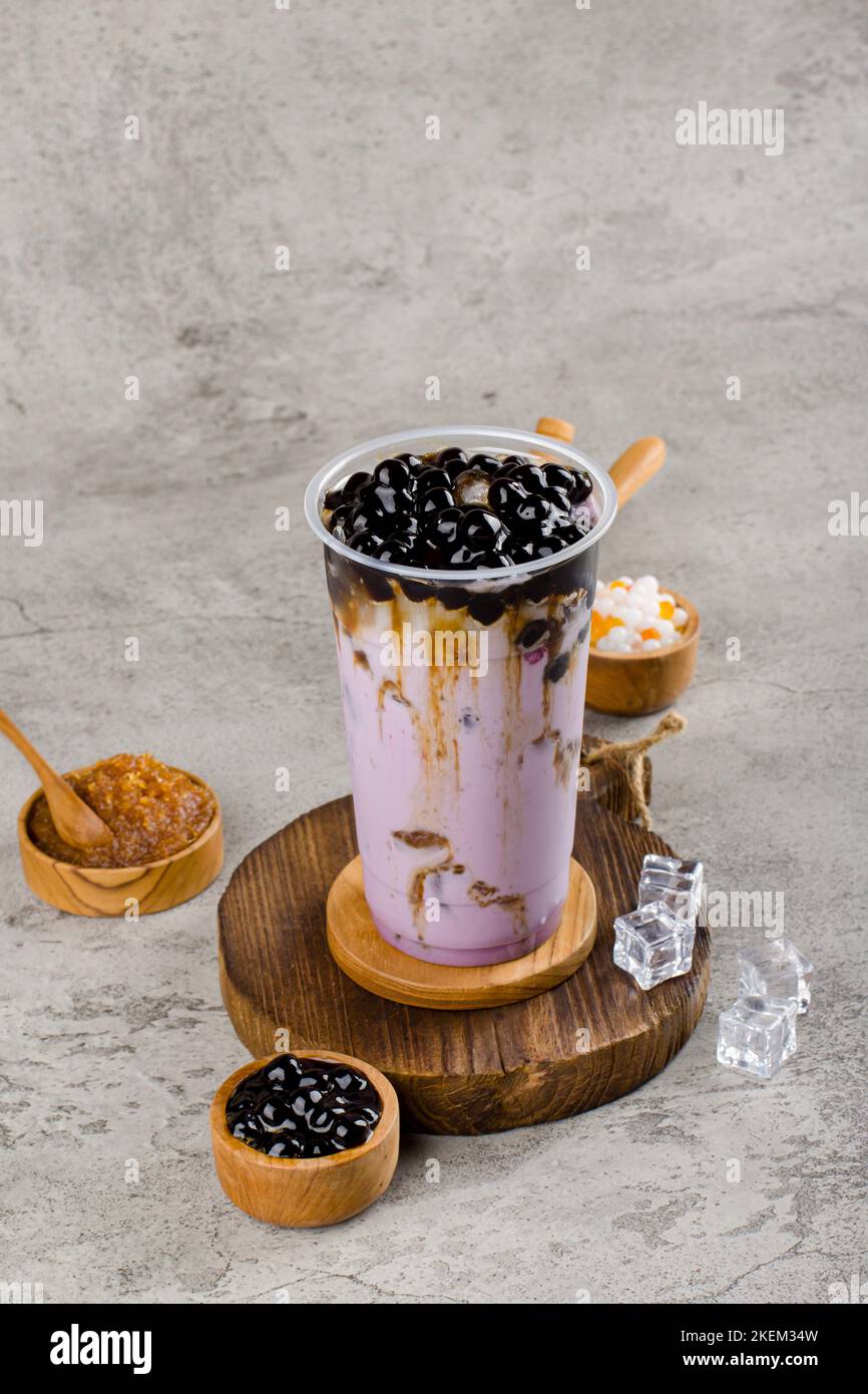 Boba oder Tapioka Perlen ist taiwan Bubble Milch Tee in Kunststoff-Tasse mit Taro-Geschmack auf Textur Hintergrund, Sommer Erfrischung. Stockfoto