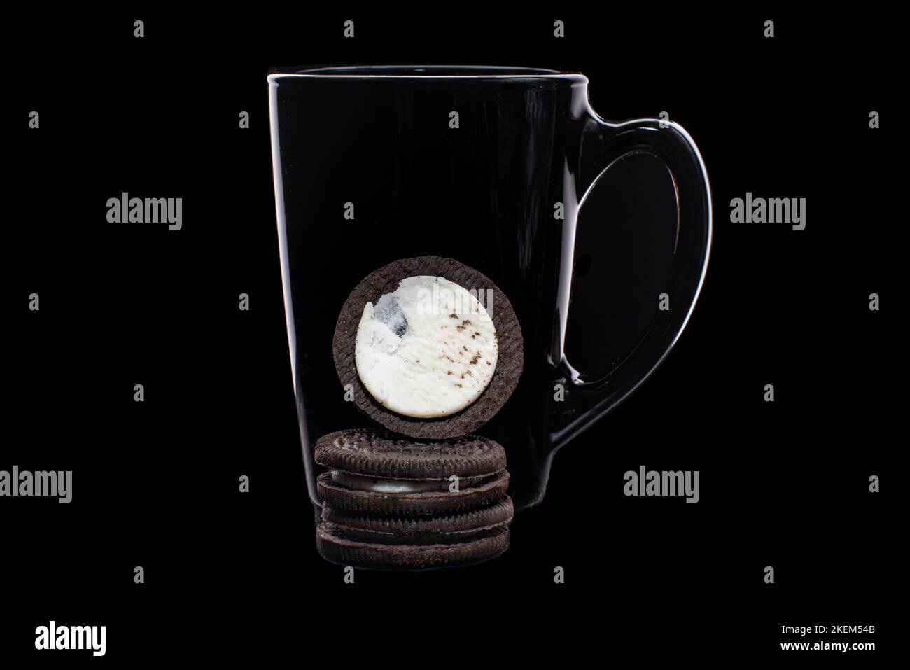 Runde Kekse mit schwarzem Becher auf schwarzem Hintergrund Stockfoto