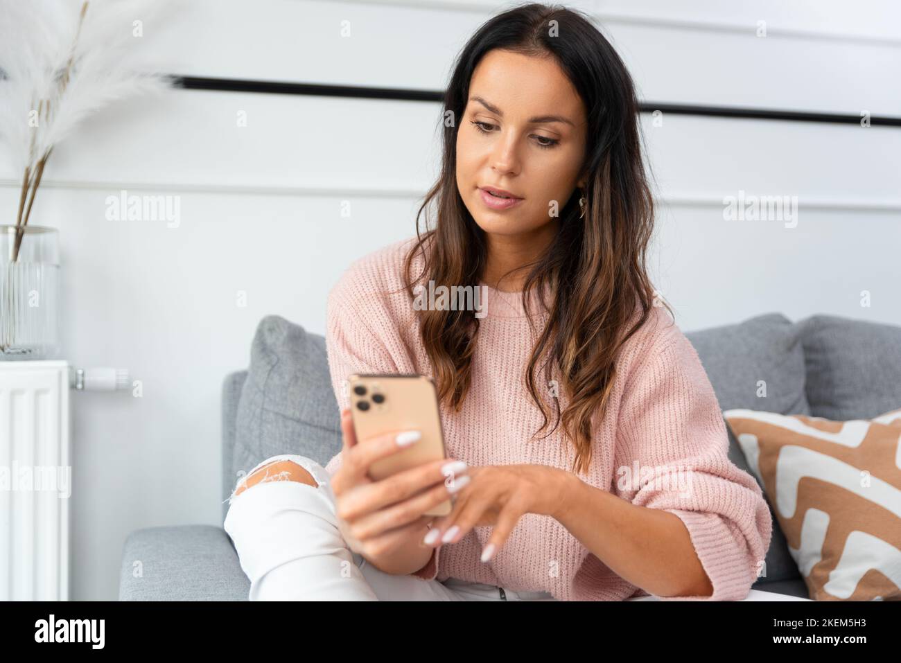Attraktive, schöne Frau, die Smartphone nutzt und zu Hause arbeitet Stockfoto