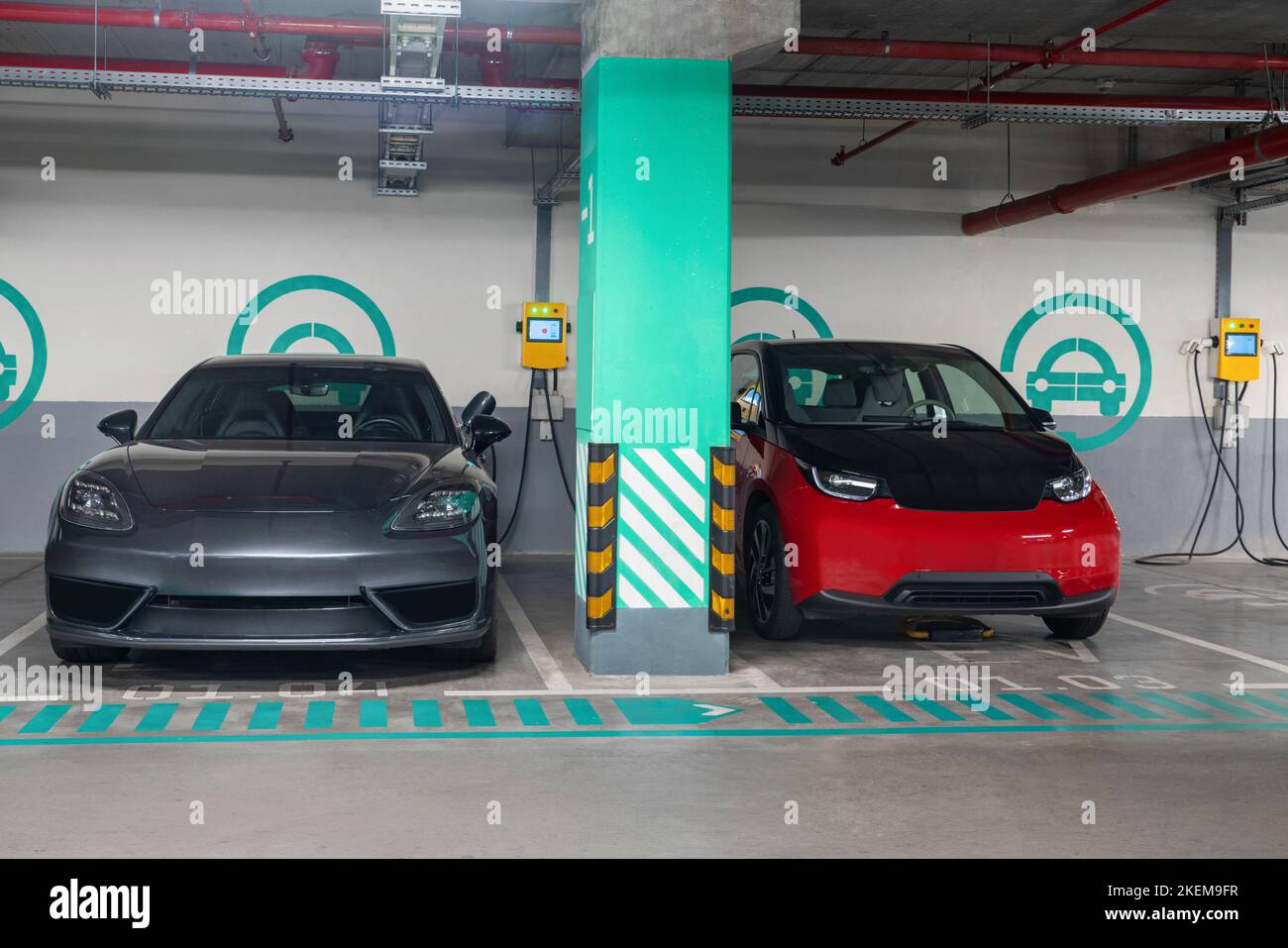 Elektroautos werden von der Ladestation in der Parkgarage des Einkaufszentrums geladen Stockfoto