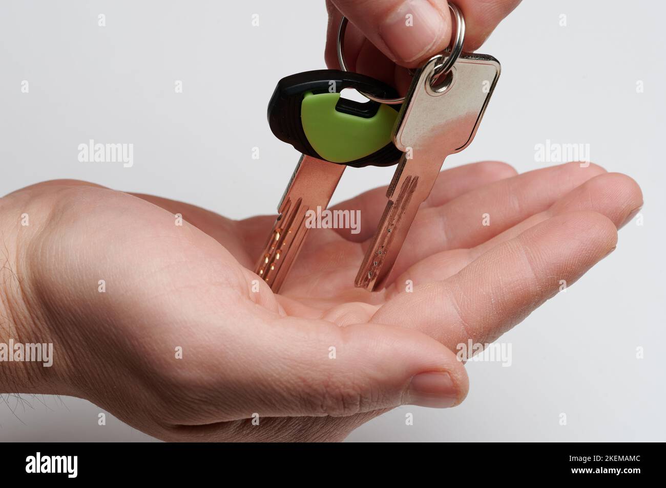Verkaufen von Eigenheims. Geben Wohnung Schlüssel zur Hand Handfläche isoliert auf Studio-Hintergrund Stockfoto