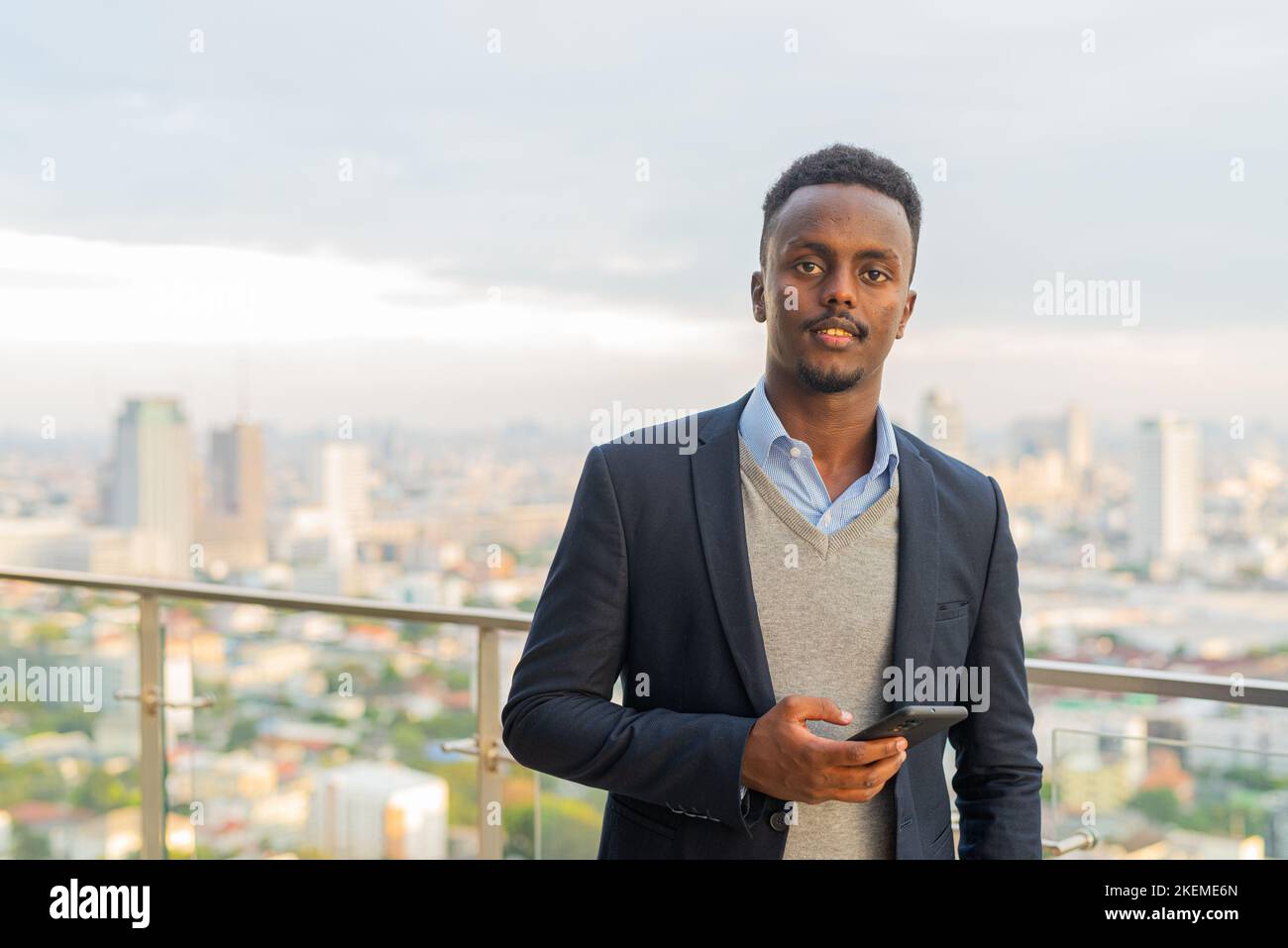 Porträt eines hübschen schwarzen afrikanischen Geschäftsmannes, der Anzug trägt und Smartphone hält Stockfoto