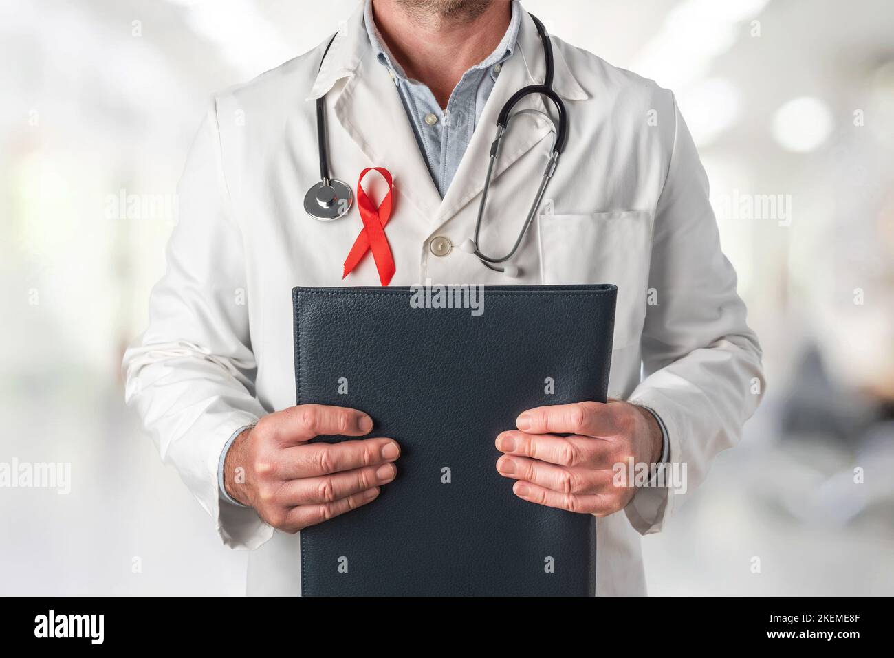 Doktor, der einen Ordner mit medizinischen Berichten hält und ein rotes Band auf seiner Brust trägt, Symbol des Welt-AIDS-Tages. Unterstützung vom Gesundheitspersonal bis hin zu Menschen Stockfoto