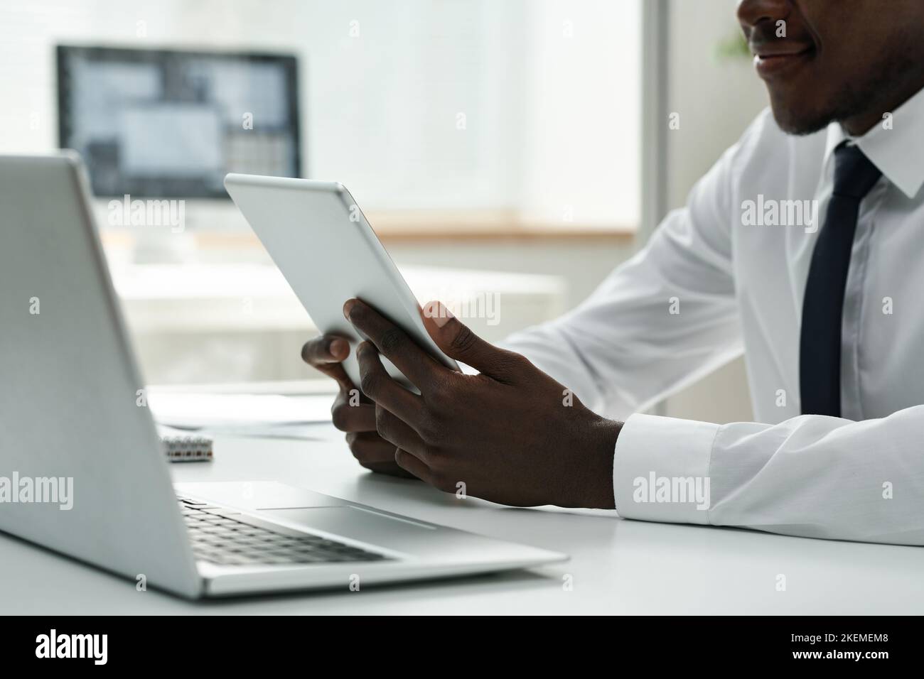 Nahaufnahme eines afroamerikanischen Geschäftsmannes, der bei seiner Arbeit ein digitales Tablet benutzte, während er am Tisch im Büro saß Stockfoto