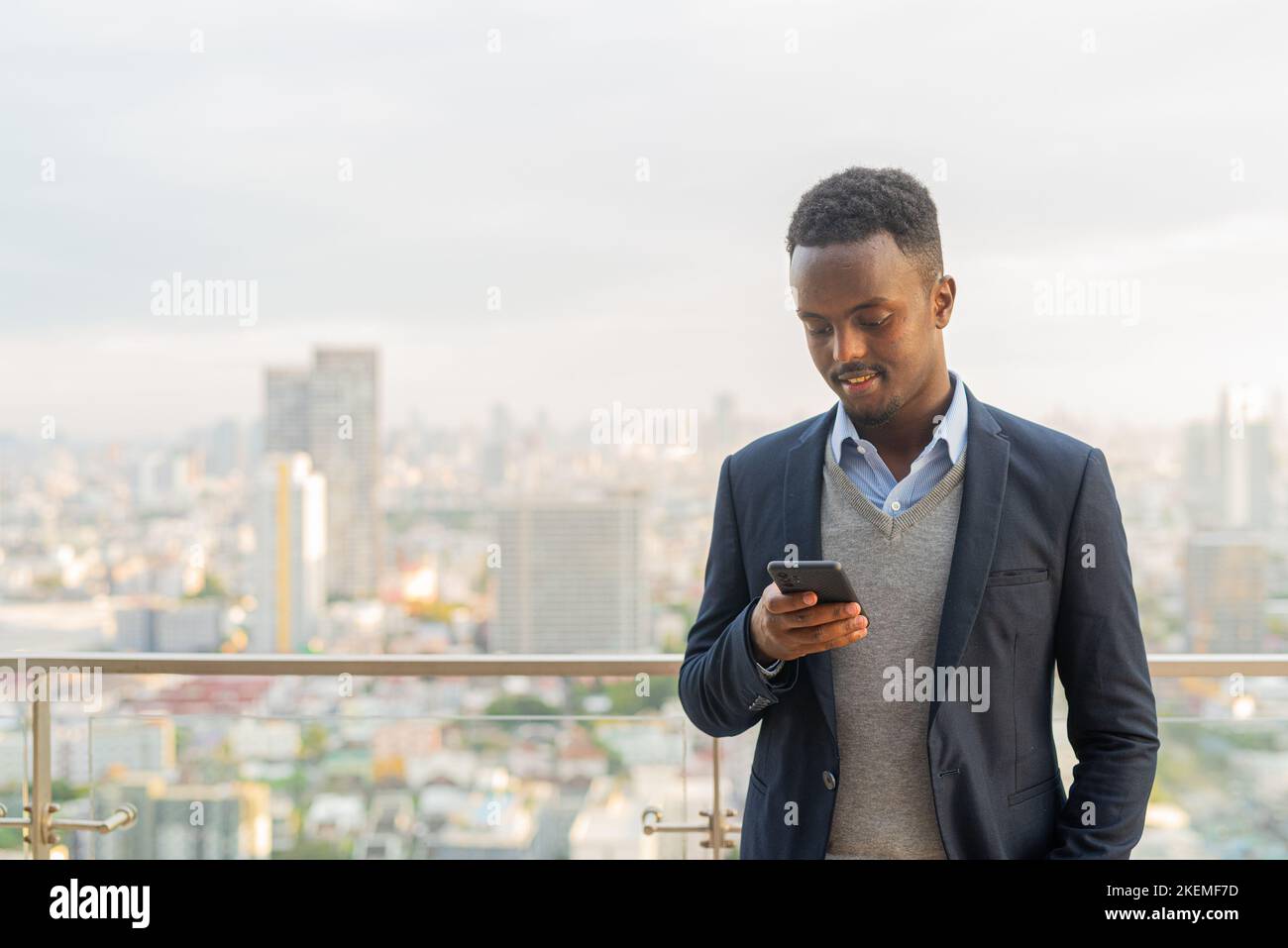 Porträt eines hübschen schwarzen afrikanischen Geschäftsmannes, der Anzug und Telefon trägt Stockfoto