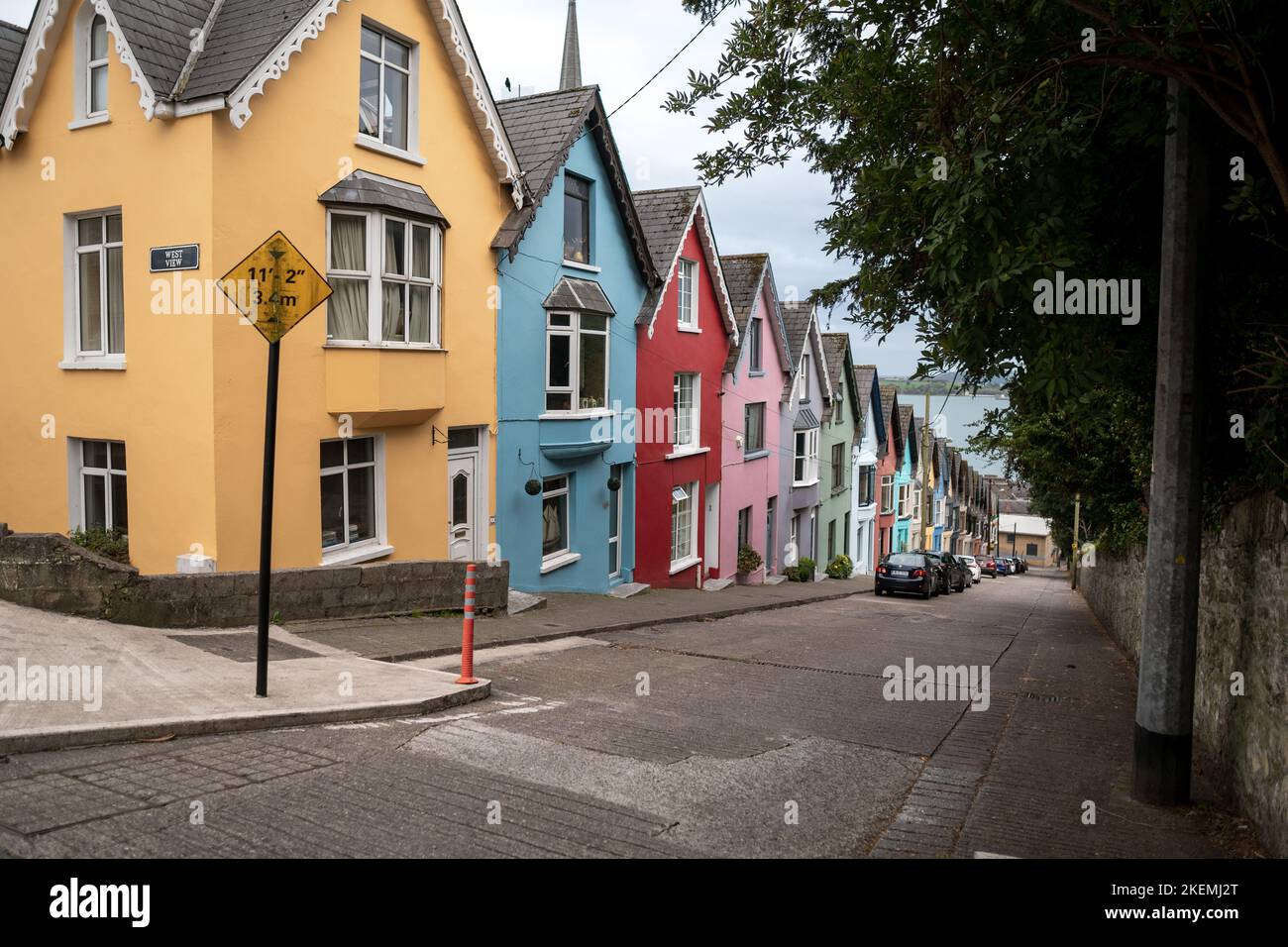 Bunte Häuserzeile mit einer imposanten Kathedrale im Hintergrund in der Hafenstadt Cobh, County Cork, Irland Stockfoto