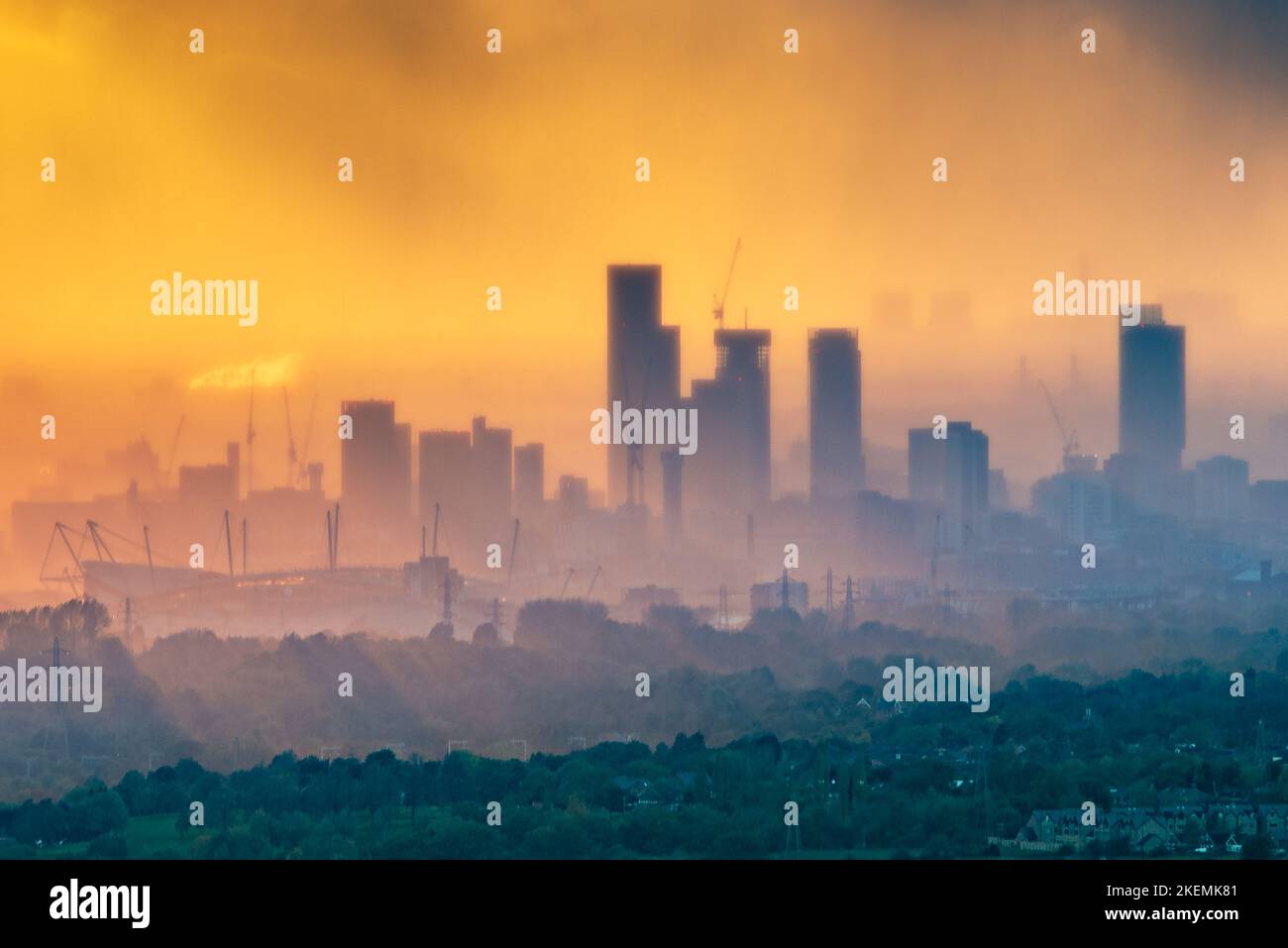 Eine Regenwolke zieht bei Sonnenuntergang über das Stadtzentrum von Manchester, von Hartshead Pike, Tameside, aus gesehen, etwa 8 Meilen (13km) vom Stadtzentrum entfernt. Stockfoto