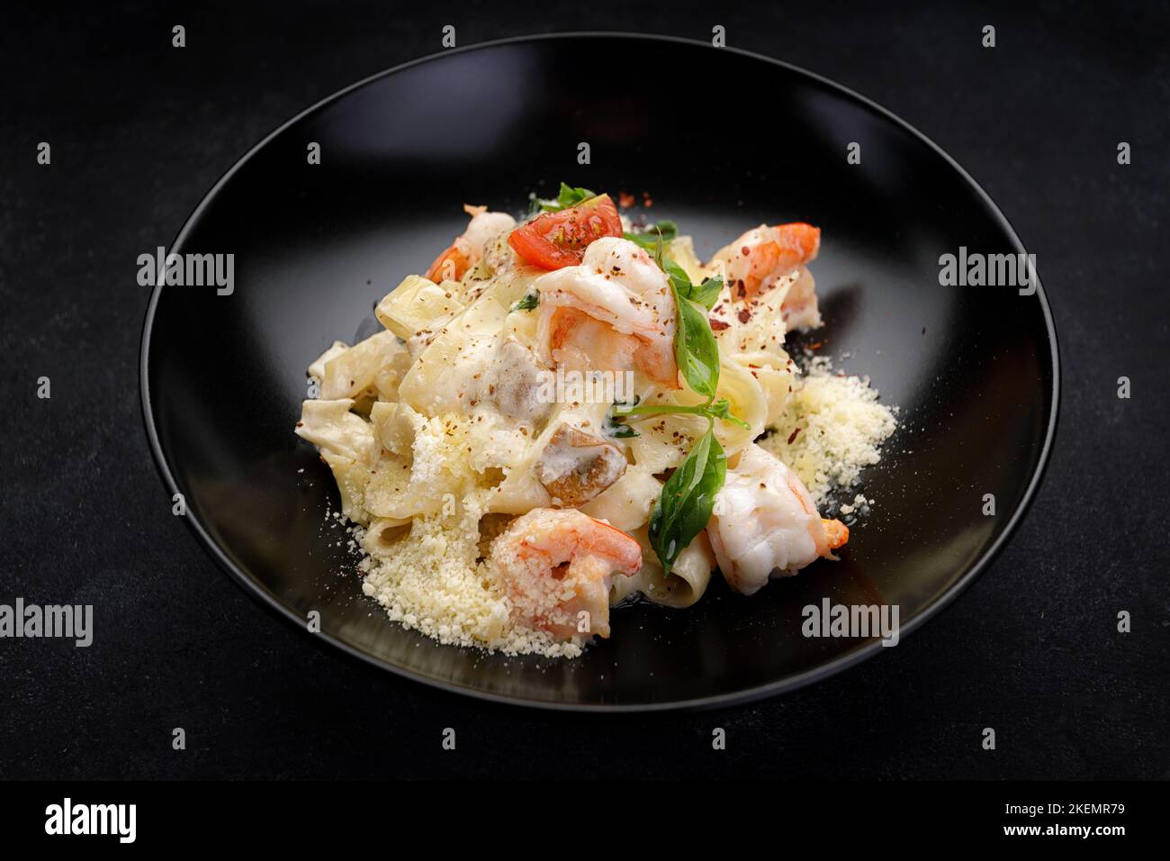 Pasta mit Garnelen, Käse, Pilzen und Gemüse auf dunklem Hintergrund Stockfoto