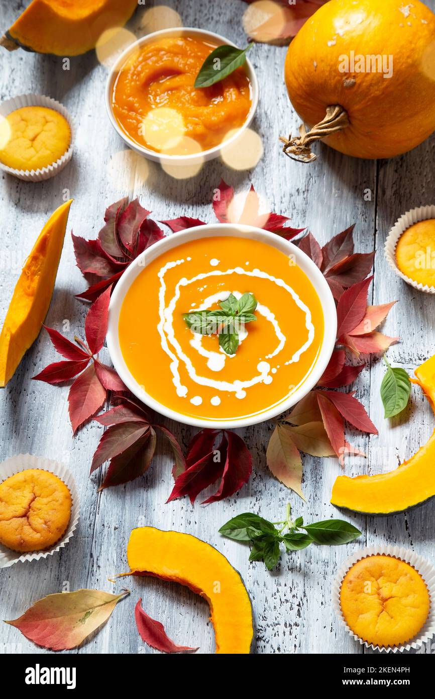 Kürbissuppe und Muffins mit dem trockenen Blätter im Herbst auf weißem Holz- Hintergrund Stockfoto