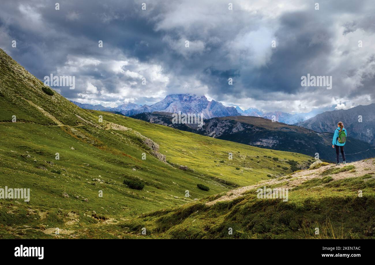 Reisen und Tourismus. Junge Frau mit Rucksack, die über einer Klippe steht und im Nebel auf die wunderschönen Berge blickt Stockfoto