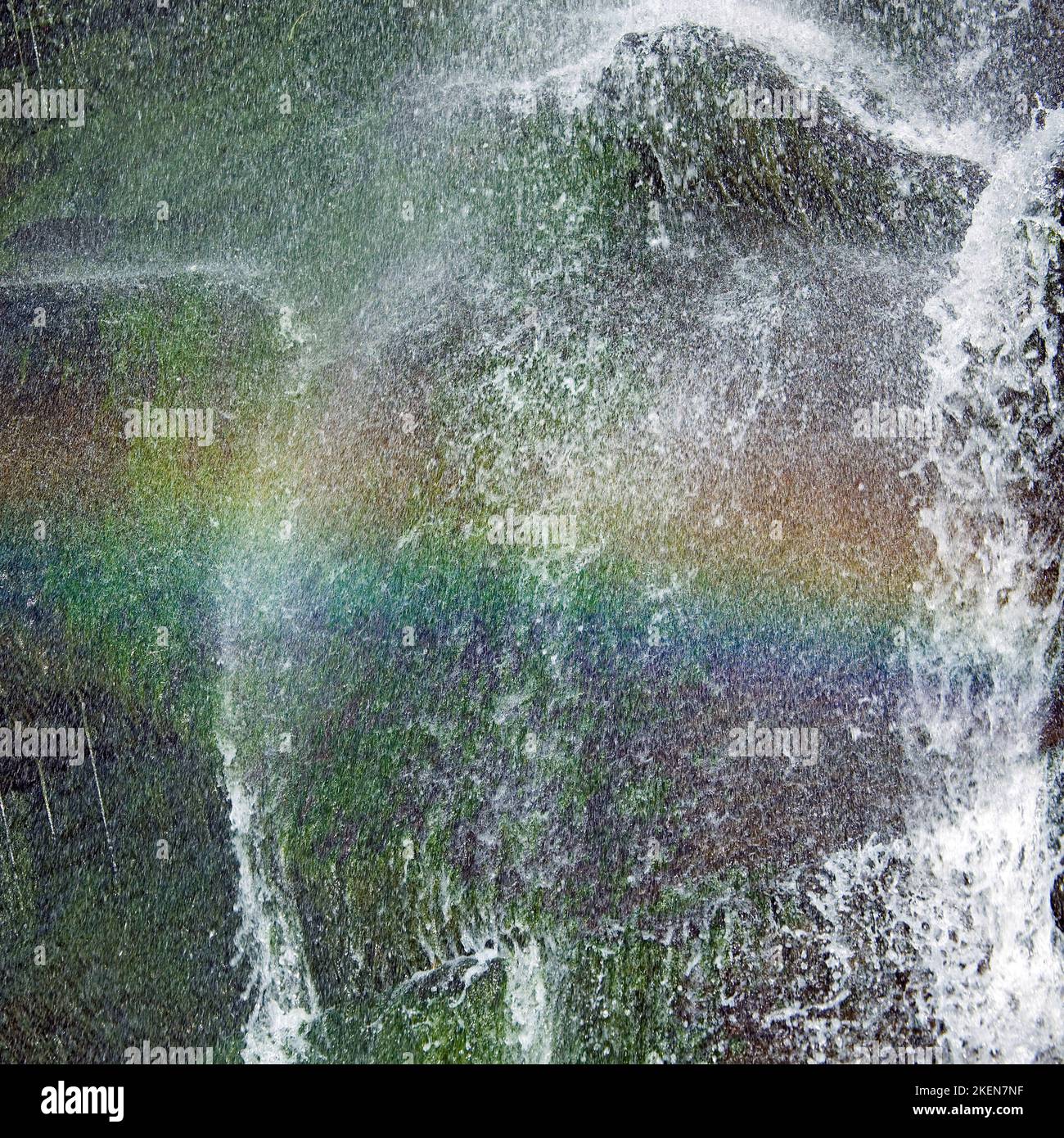 Nahaufnahme eines Strandwasserfalls, der einen Regenbogen in der Sprühflut des Tresaith Beach Cardigan Bay Wales zeigt Stockfoto