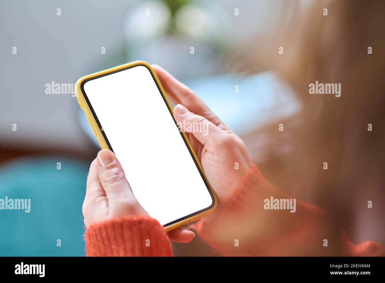 Frau hält Mobiltelefon in den Händen mit weißem Mockup-Bildschirm für Werbung. Stockfoto