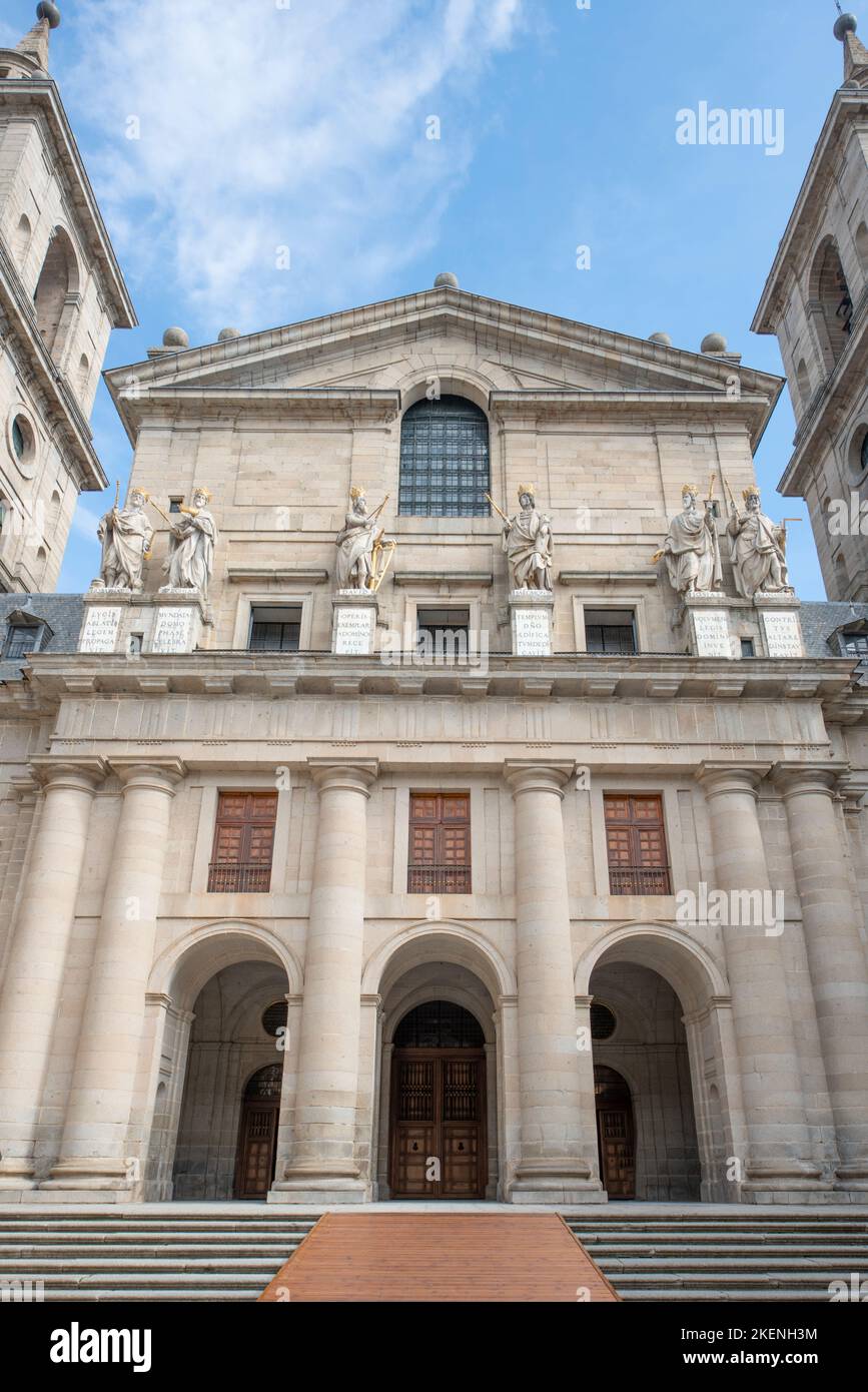 Fassaden des Klosters El Escorial in Madrid an einem Tag blauen Himmels mit weißen Wolken mit Statuen verschiedener historischer Könige Stockfoto