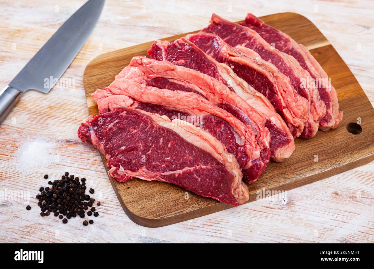 Rohes marmoriertes Rindfleisch mit Pfefferkorn auf Holzoberfläche Stockfoto